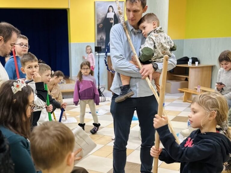 Aktor podczas próby do przedstawienia pt. Złota Rybka trzymający dziecko na rękach